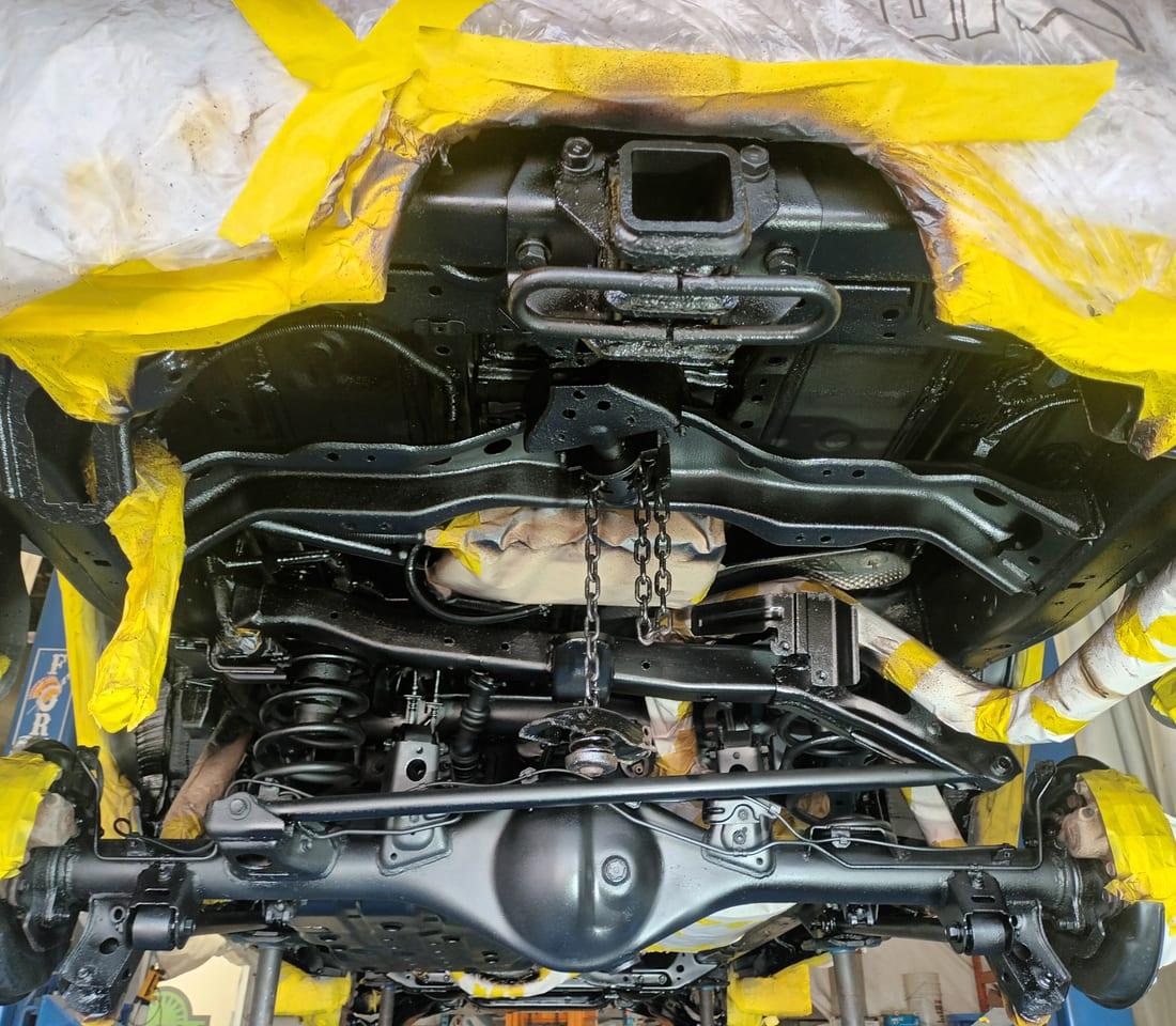 Masked vehicle underbody on the lift, freshly coated, at RBSD in Hamilton